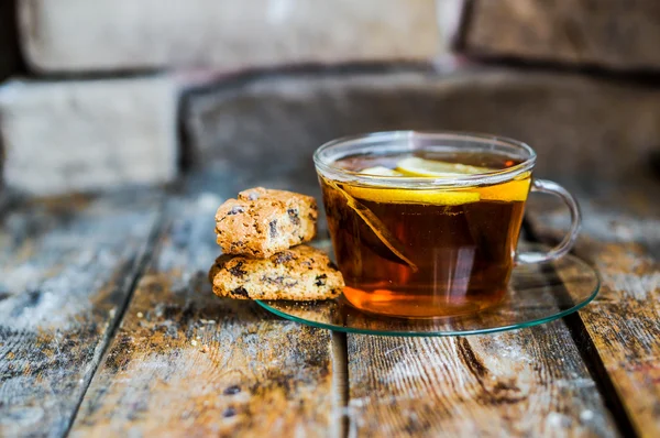 Xícara de chá com limão e biscoitos no fundo de madeira rústica — Fotografia de Stock