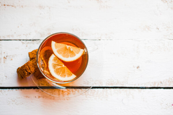 Tea cup with lemon and cookies on rustic wooden background