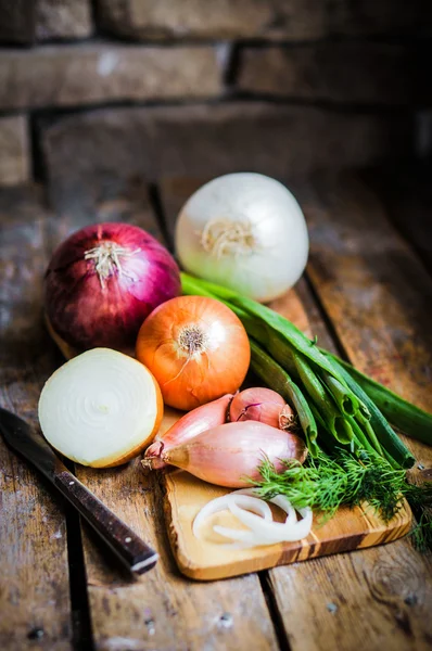 Πολύχρωμο κρεμμύδια και το σκόρδο σε ρουστίκ ξύλινα φόντο — Φωτογραφία Αρχείου