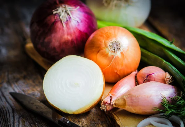 Bunte Zwiebeln und Knoblauch auf rustikalem Holzgrund — Stockfoto