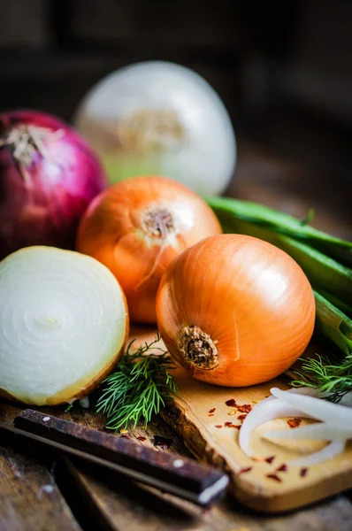 Kleurrijke uien en knoflook op rustieke houten achtergrond — Stockfoto