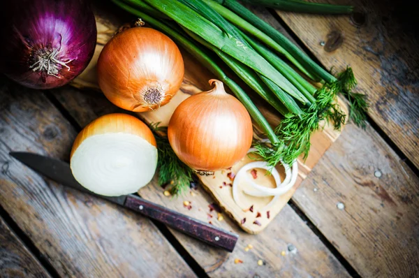 Bunte Zwiebeln und Knoblauch auf rustikalem Holzgrund — Stockfoto