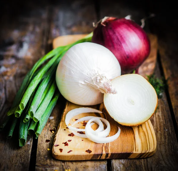 Colorful onions and garlic on rustic wooden background — Stock Photo, Image