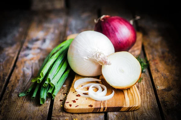 Kleurrijke uien en knoflook op rustieke houten achtergrond — Stockfoto