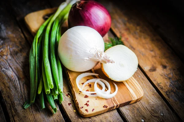 Bunte Zwiebeln und Knoblauch auf rustikalem Holzgrund — Stockfoto