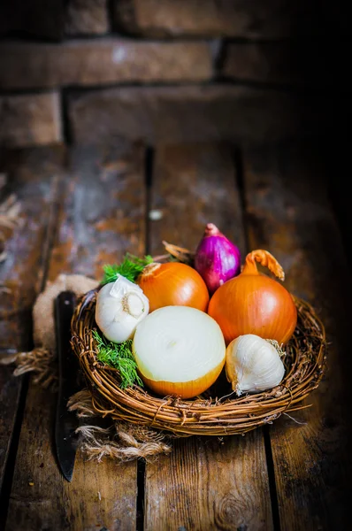 Kleurrijke uien en knoflook op rustieke houten achtergrond — Stockfoto