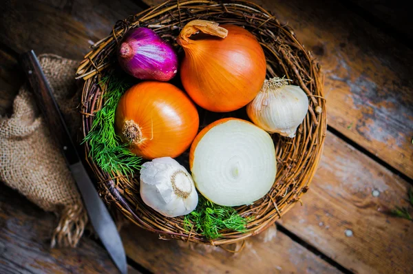 Cebolas coloridas e alho no fundo de madeira rústica — Fotografia de Stock