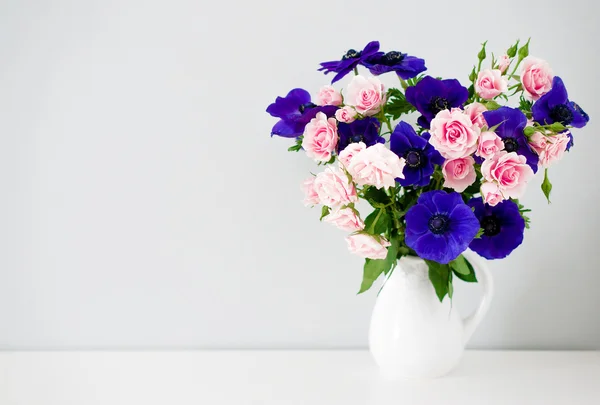 Bouquet of pink roses and blue anemones in white vase — Stock Photo, Image