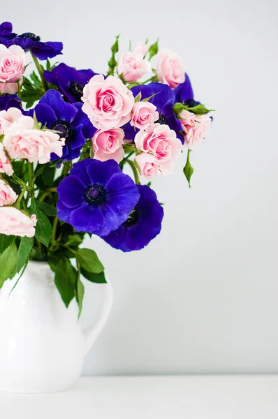 Bouquet de roses roses et anémones bleues en vase blanc — Photo