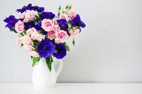 Ramo de rosas rosadas y anémonas azules en jarrón blanco — Foto de Stock