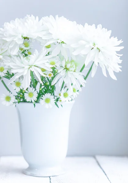 Marguerites en vase blanc sur fond bois — Photo