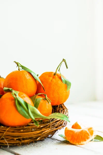 Mandarinky v koši na dřevěné pozadí — Stock fotografie