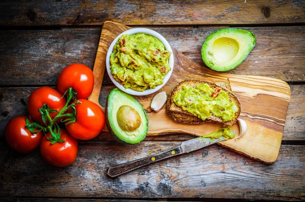 Guacamaole with bread and avocado on rustic wooden background — Stock Photo, Image