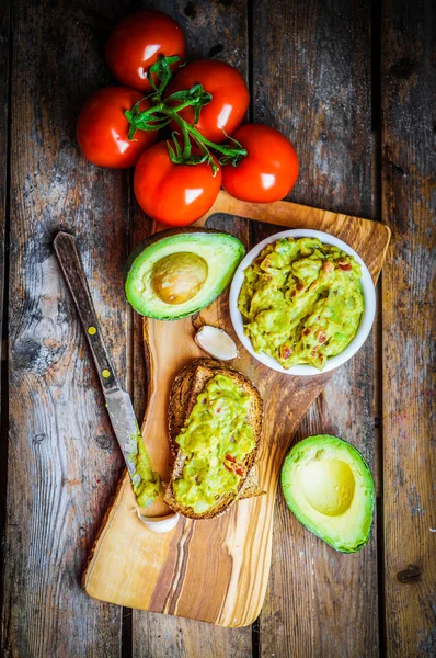 Guacamaole with bread and avocado on rustic wooden background — Stock Photo, Image