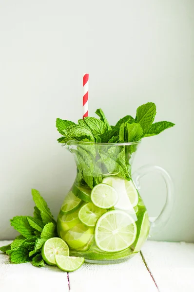 Water with limes and mint on wooden background — Stock Photo, Image