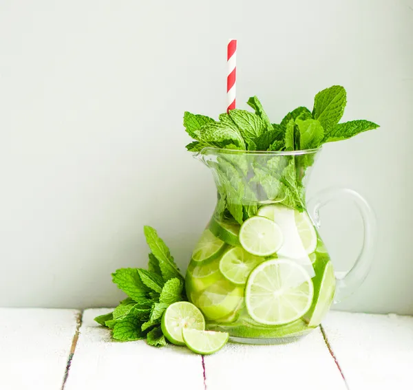 Water met limoenen (lemmetjes) en mint op houten achtergrond — Stockfoto