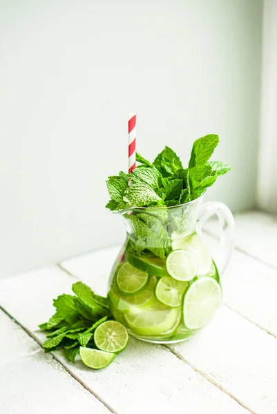Water with limes and mint on wooden background — Stock Photo, Image