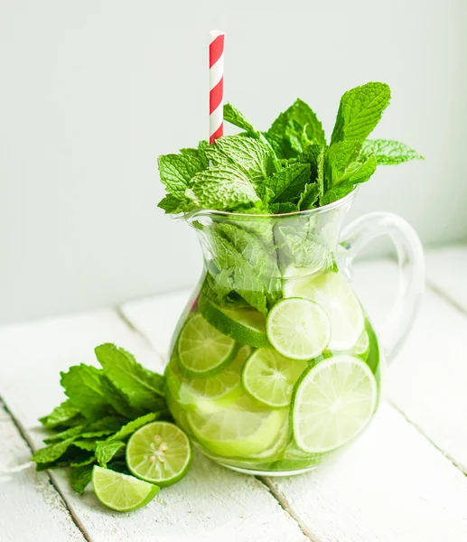 Water with limes and mint on wooden background — Stock Photo, Image