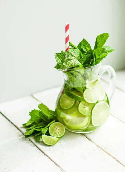 Water met limoenen (lemmetjes) en mint op houten achtergrond — Stockfoto