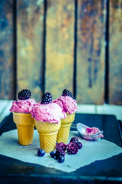 Ice - cream in kegels met bessen op rustieke houten achtergrond — Stockfoto