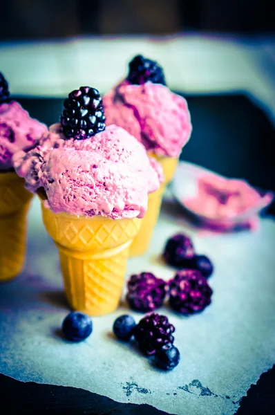 Gelato in coni con bacche su fondo rustico in legno — Foto Stock