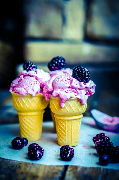 Gelato in coni con bacche su fondo rustico in legno — Foto Stock