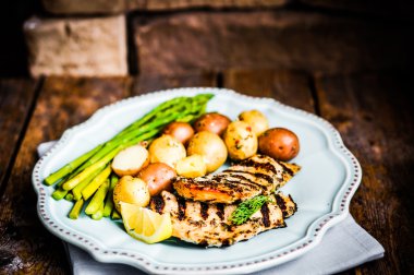 ızgara tavuk patates ve ahşap zemin üzerinde kuşkonmaz ile