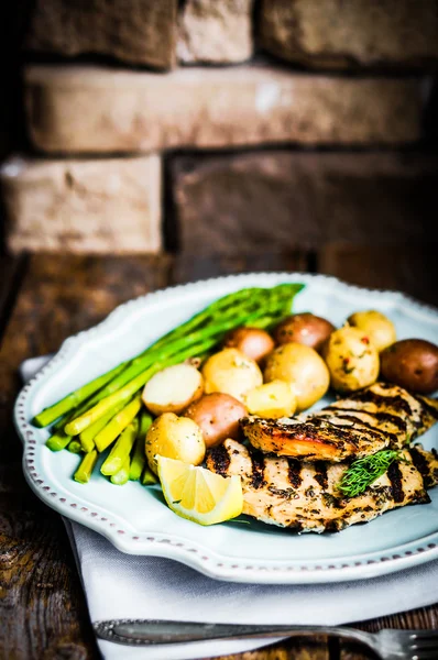 Frango grelhado com batatas e aspargos no fundo de madeira — Zdjęcie stockowe