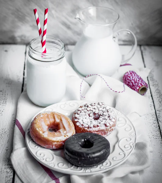 Milk and assorted donuts on rustic wooden background — Stock Photo, Image