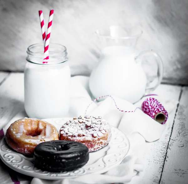Milk and assorted donuts on rustic wooden background — Stock Photo, Image