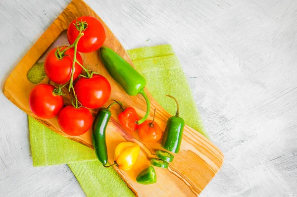 Verschiedene Paprika und Tomaten auf Holzgrund — Stockfoto