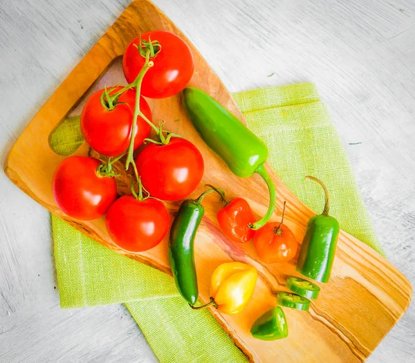 Verschiedene Paprika und Tomaten auf Holzgrund — Stockfoto