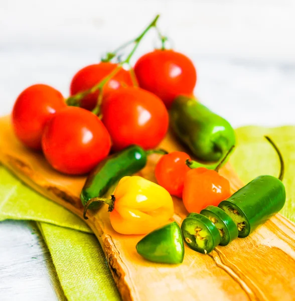 Verschiedene Paprika und Tomaten auf Holzgrund — Stockfoto