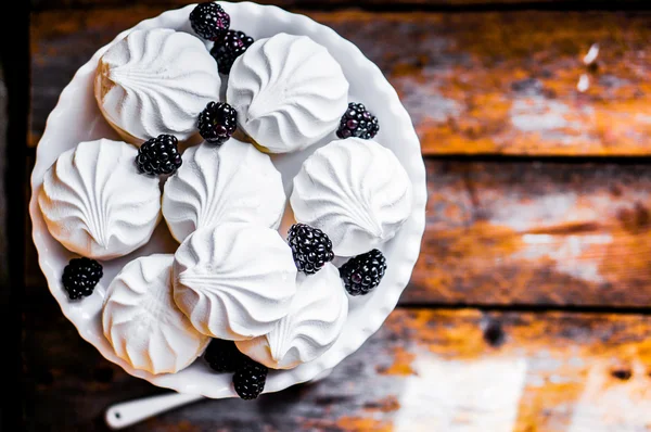 Meringue cookies witj blackberries on rustic background — Stock Photo, Image