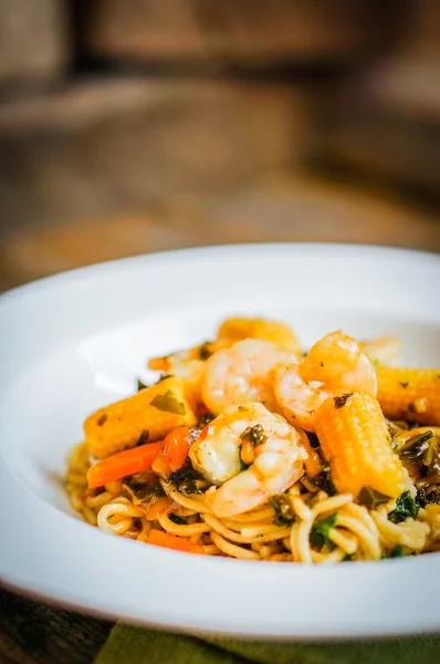 意大利面食与虾和蔬菜上木制的背景 — Stockfoto