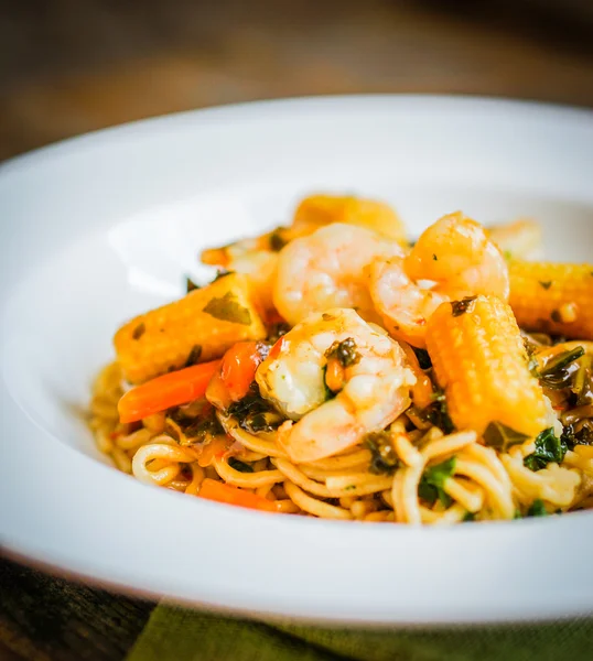 Italské těstoviny s krevetami a zeleninou na dřevěné pozadí — Stock fotografie