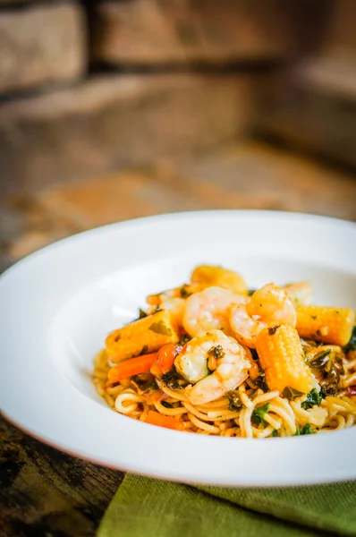 意大利面食与虾和蔬菜上木制的背景 — Stockfoto