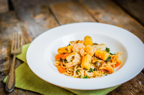 Pastas italianas con gambas y verduras sobre fondo de madera — Foto de Stock