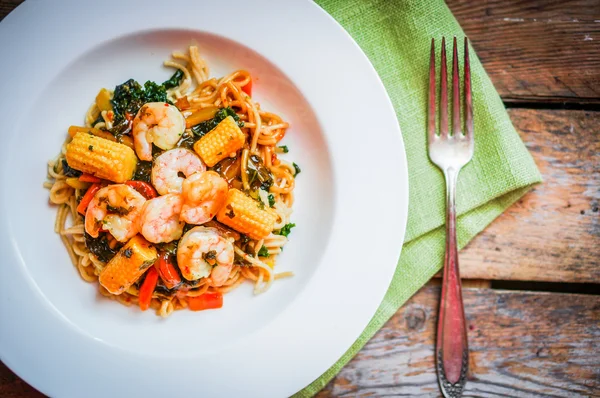 意大利面食与虾和蔬菜上木制的背景 — 图库照片