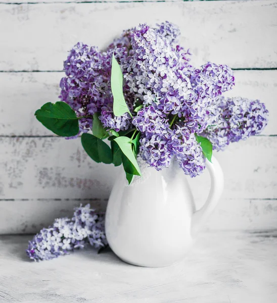 Flieder in weißer Vase auf rustikalem Hintergrund — Stockfoto