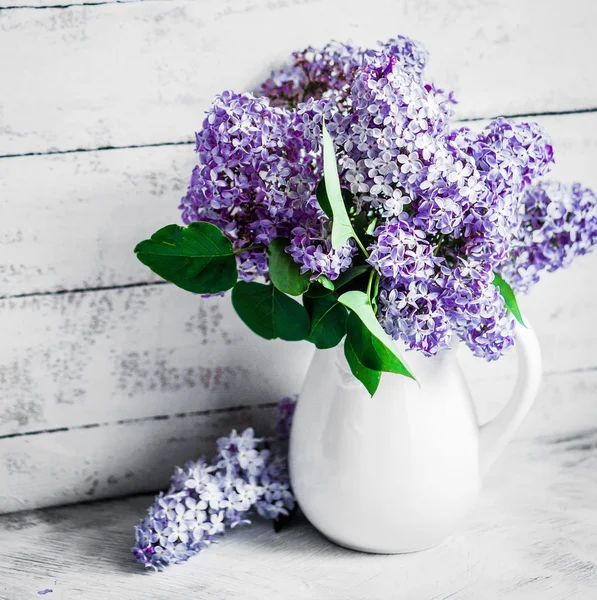 Flieder in weißer Vase auf rustikalem Hintergrund — Stockfoto