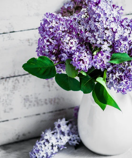 Šeříky v bílé vázy na rustikální pozadí — Stock fotografie