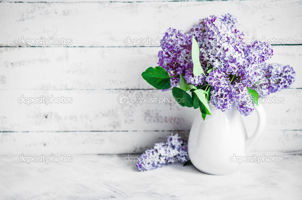 Lilacs in white vase on rustic background