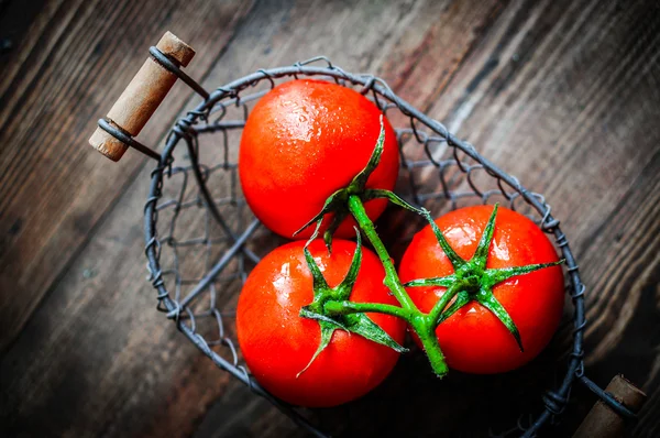 Tomates frescos en canasta antigua sobre fondo de madera — Foto de Stock