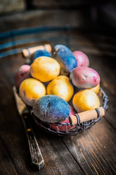 Red,blue and yellow potatoes on wooden background — Stock Photo, Image