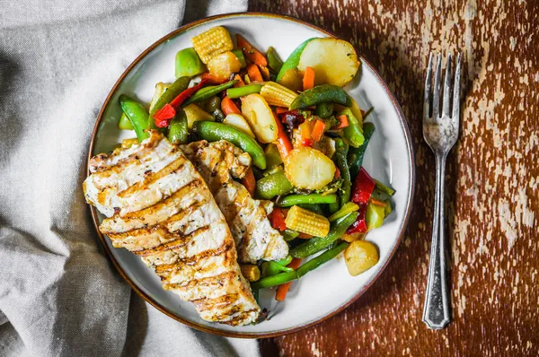 Жареная курица с запечёнными овощами на деревенском фоне — стоковое фото