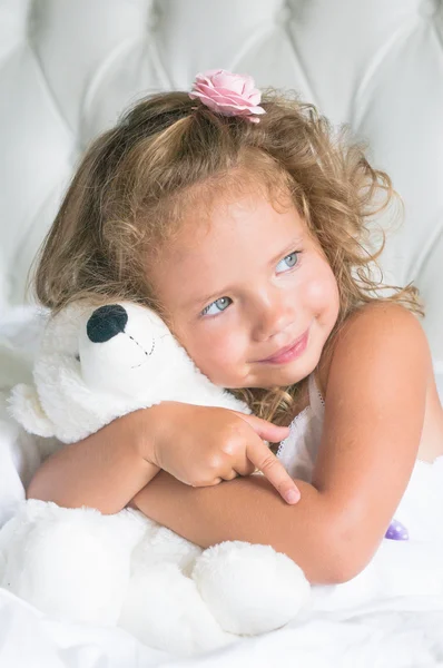 Cute baby girl with teddy bear in white bed — Stock Photo, Image