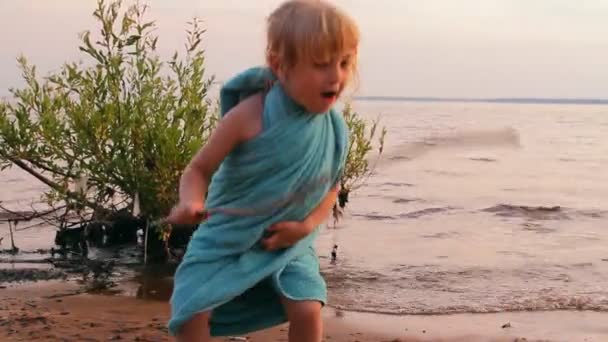 Little girl plays, looks afar at water — Stock Video