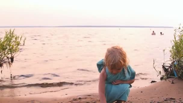 Little girl plays, looks afar at water — Stock Video