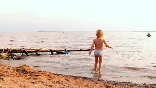 Маленькая девочка кружит в воде, собирается искупаться — стоковое видео